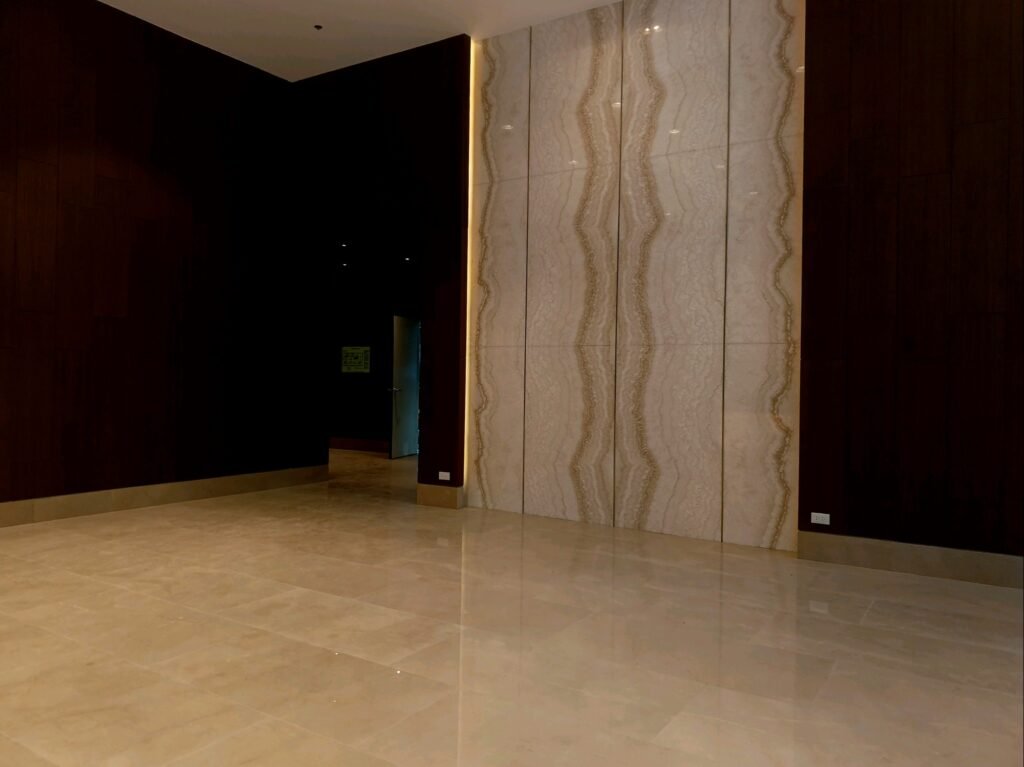 Spacious room with polished marble floors, dark wood-paneled walls, and a large decorative stone accent wall.