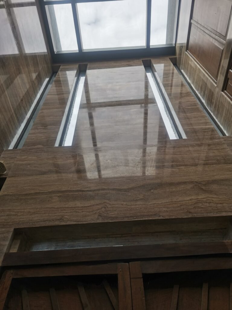 View looking up at a polished marble wall with two narrow vertical windows and a large window at the top letting in natural light.