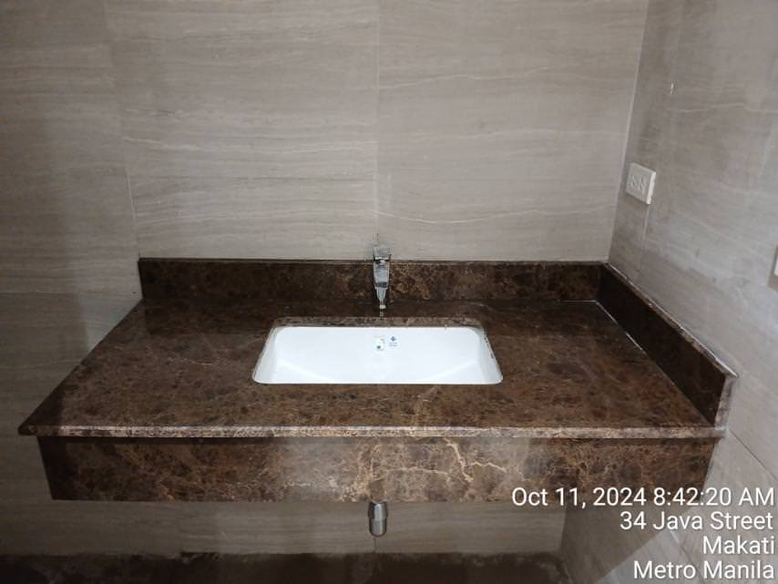 A rectangular sink with a marble countertop is installed against a beige tiled wall. A timestamp and location details are visible at the bottom right.