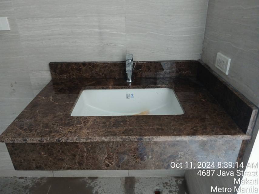 Rectangular sink with a dark brown marble countertop, chrome faucet, wall outlet, and timestamp in a tiled bathroom setting.